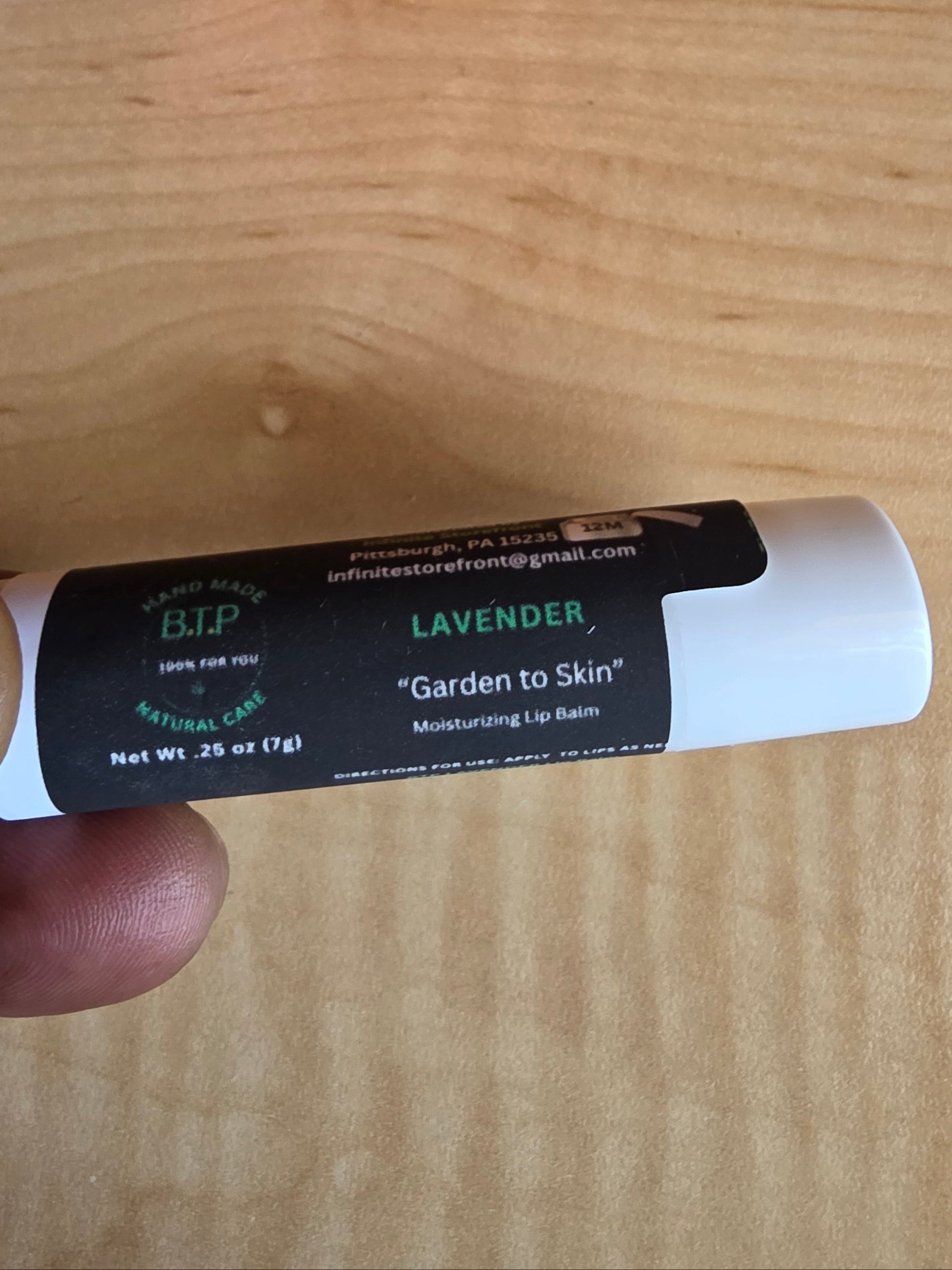 Lip balm tube held by a hand on a wooden surface