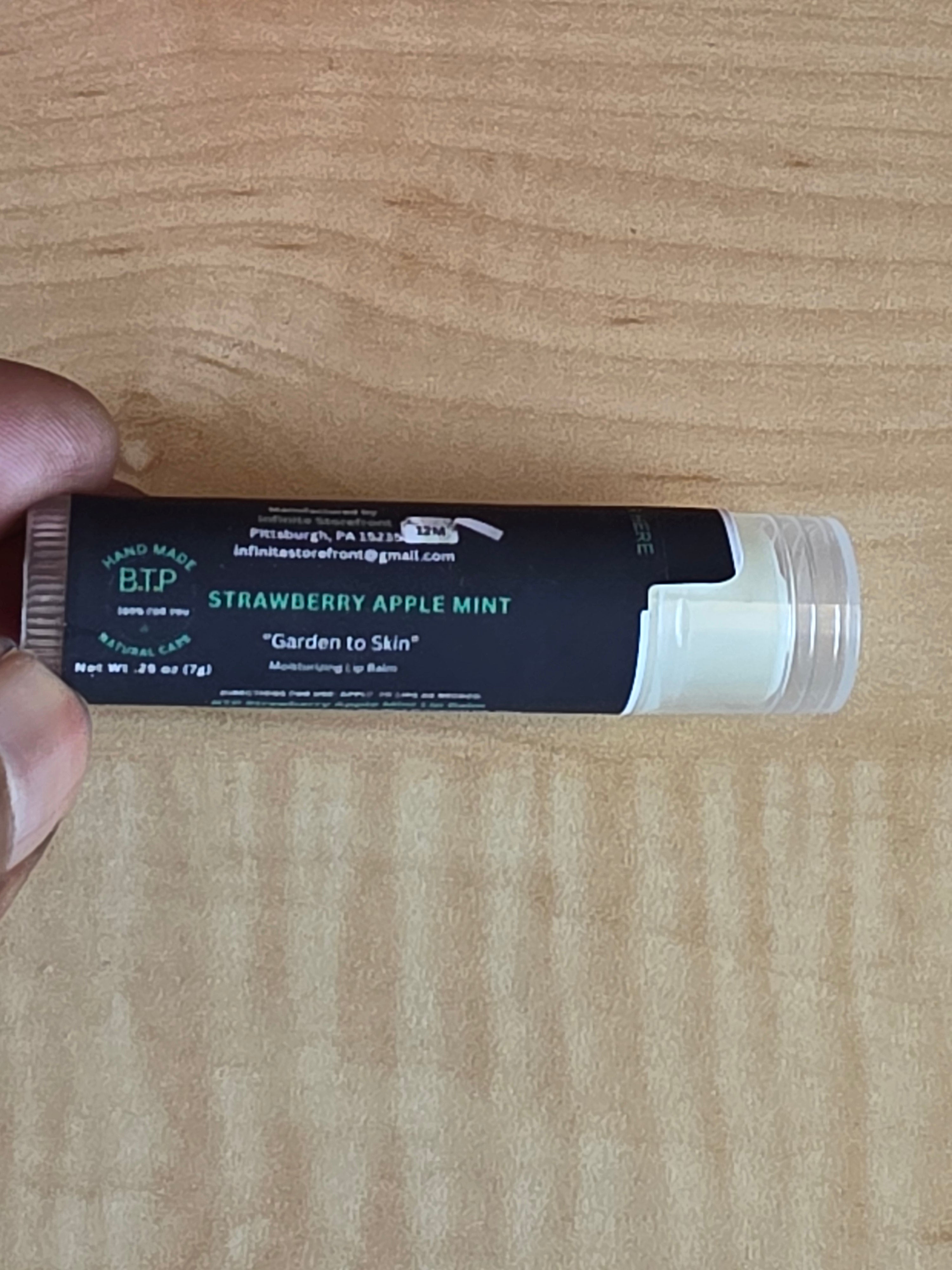 Lip balm tube with visible branding on a wooden surface