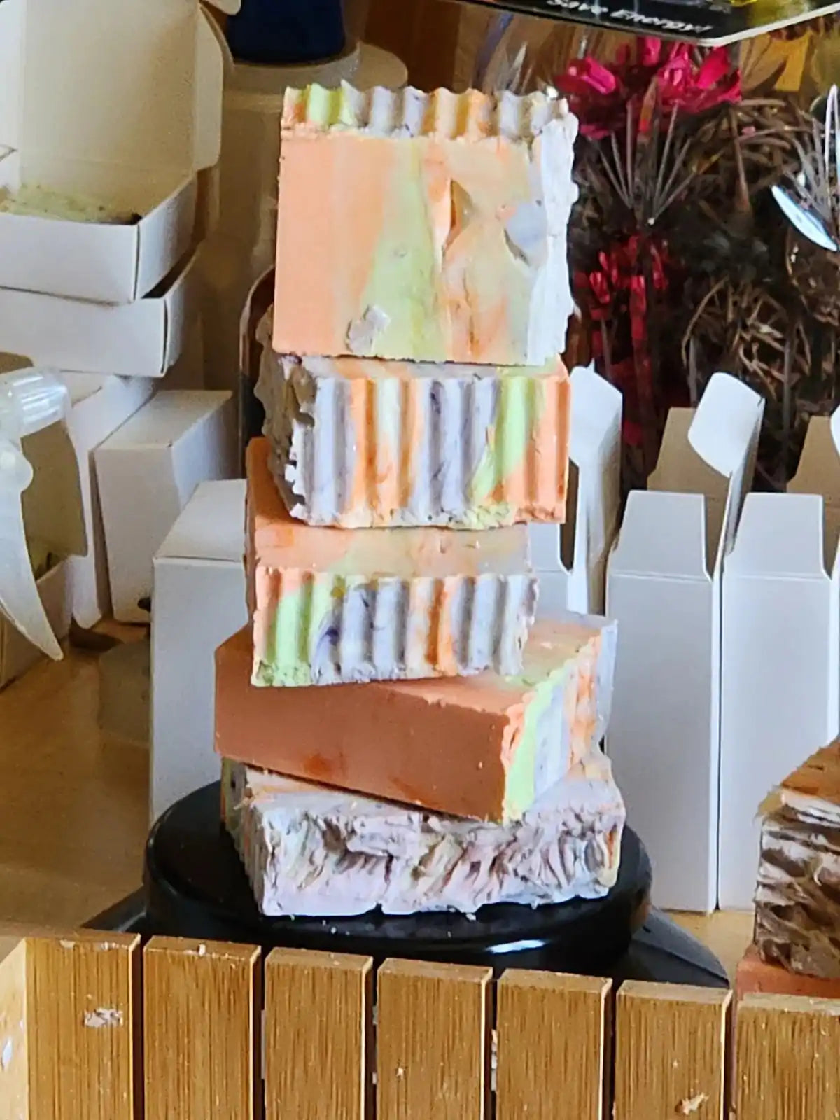 Stack of colorful soap bars on a wooden surface with a blurred background
