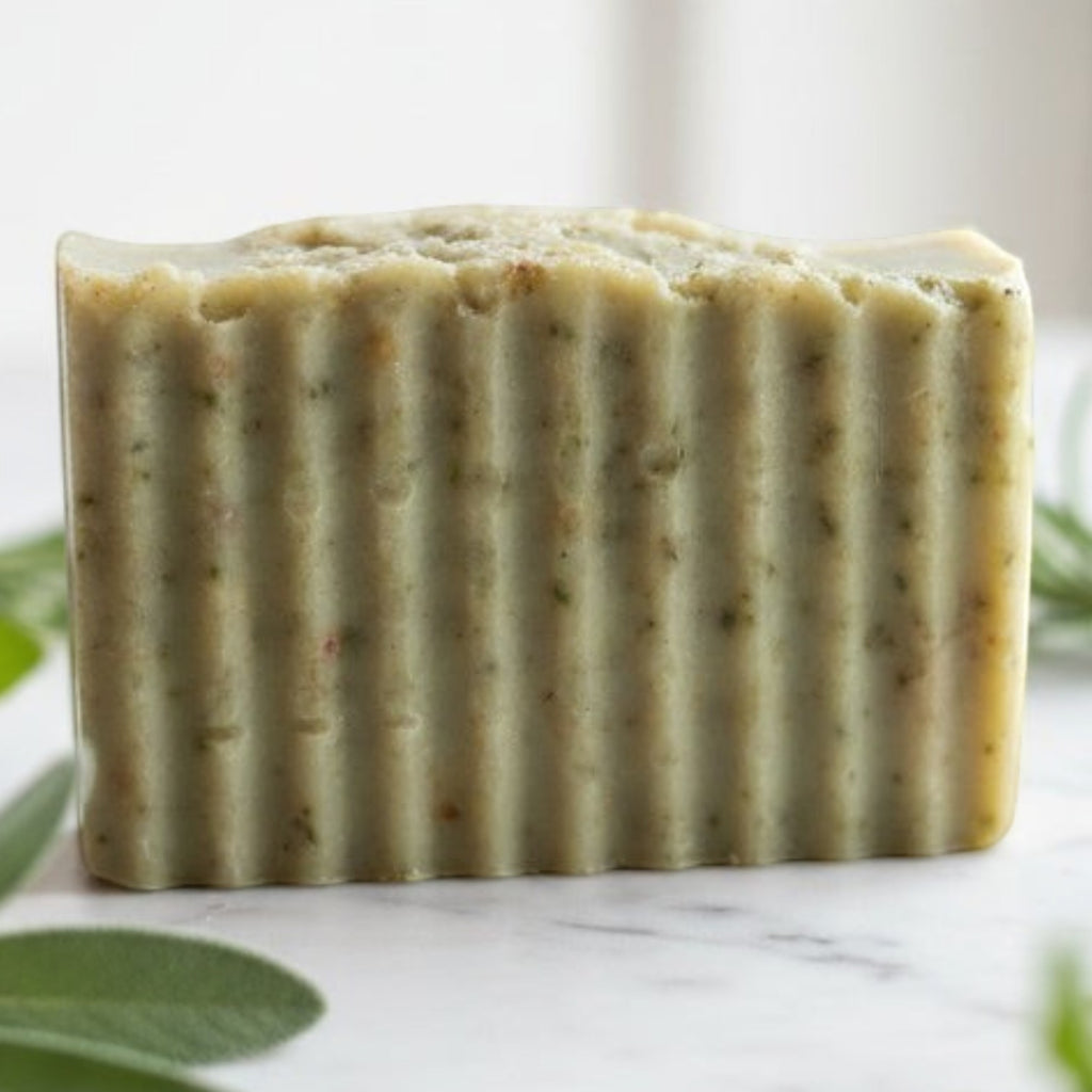 Infinite Storefront Escape handmade natural body soap bar with textured surface on a marble surface with fresh herbs.
