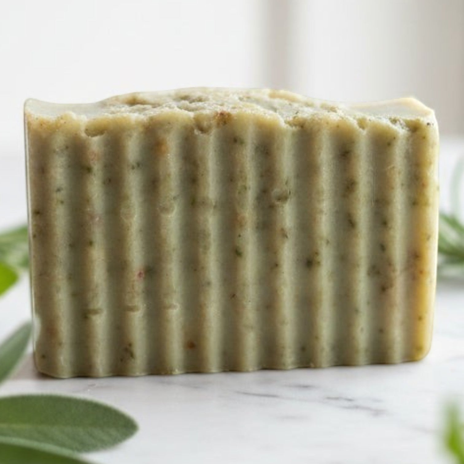 Infinite Storefront Escape handmade natural body soap bar with textured surface on a marble surface with fresh herbs.