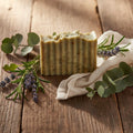 Infinite Storefront handmade natural body soap with textured edges, cucumber and lemon, on a rustic wooden surface.