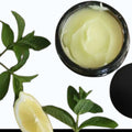 Infinite Storefront lemon balm and peppermint body balm in a black jar surrounded by fresh mint leaves and lemon slices